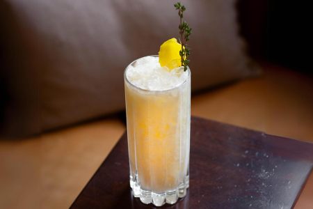 Yellow cocktail with lemon and thyme in a collins glass