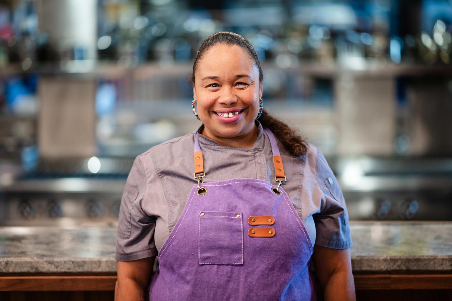 Chef Crystal Wahpepah in a purple apron smiling in her kitchen