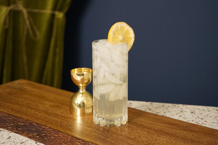 a boozy lemonade sits on a counter with lemon