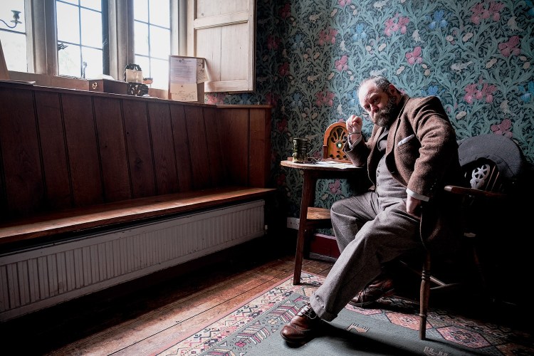 Man in suit sitting in a living room looking into the camera