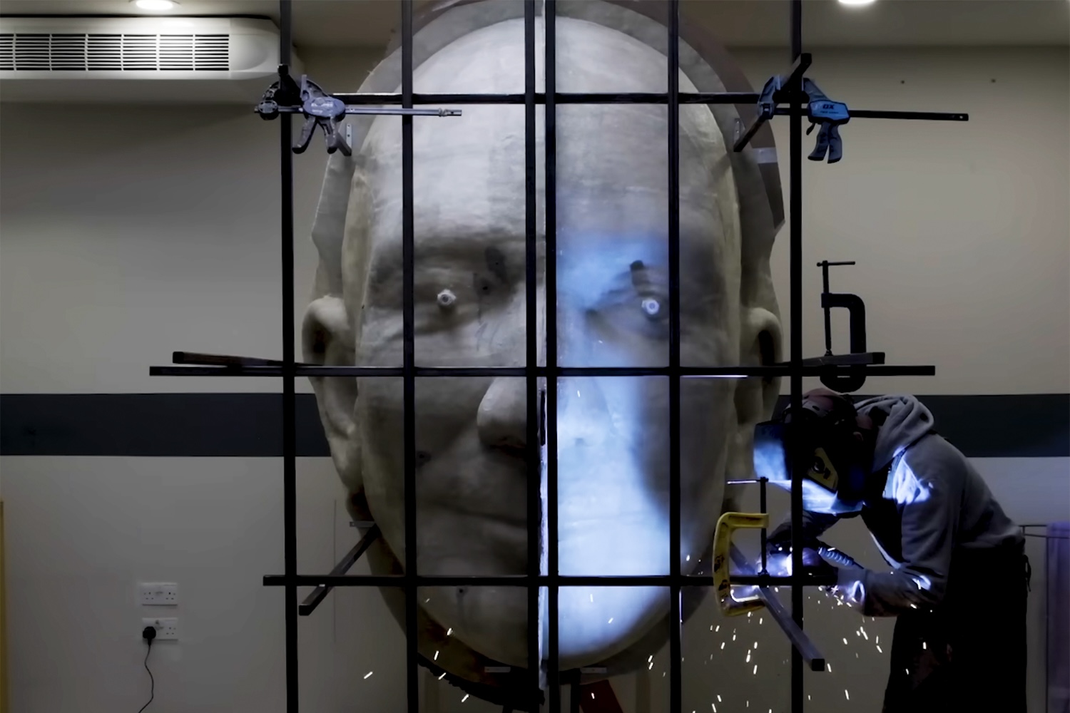 Giant sculpture of Jeff Bezos' head suspended with black bars